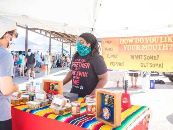 Person selling salsa to another person at a farmer's market