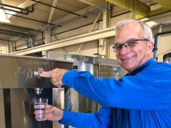 Man dispensing water into a cup from a fountain