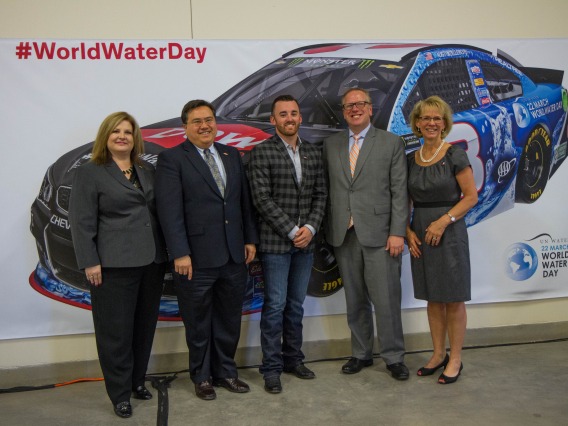 Group of people standing in front of World Water Day NASCAR poster.