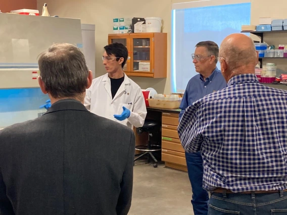 A person in a lab coat talks to a small group