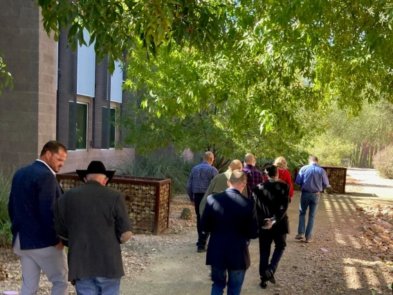 A group of people walk on a path with trees next to a building