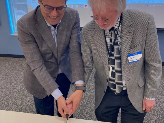 Two men cutting celebratory cake.