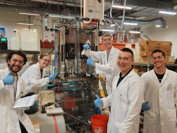 Students wearing lab coats working with water purification equipment