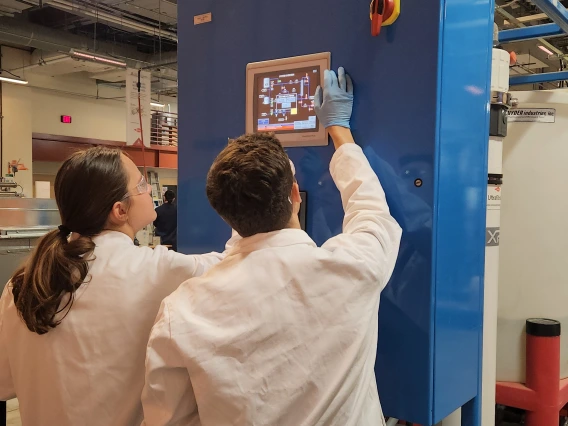 Two workers reading laboratory instrument screen