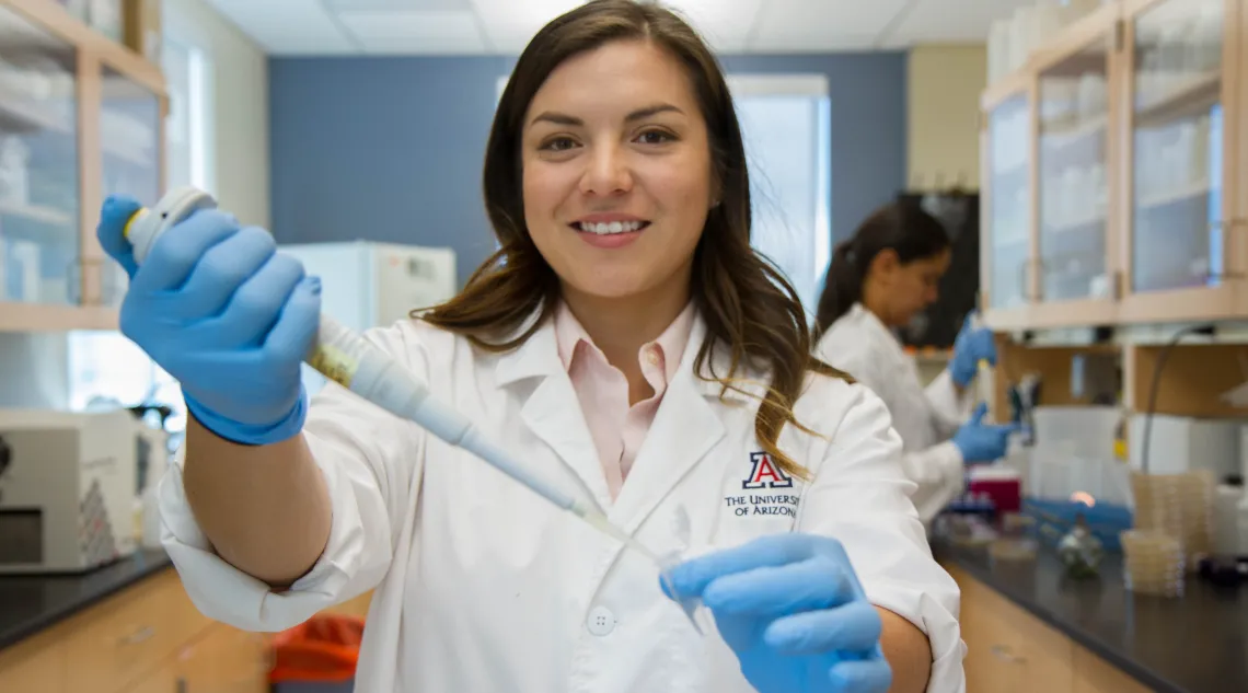 Student in lab coat using scientific equipment