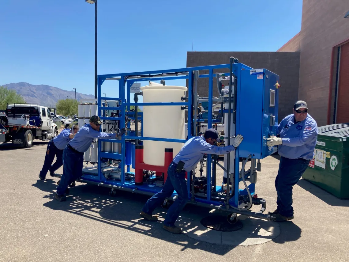 Water reuse equipment being moved into the WEST center by workers