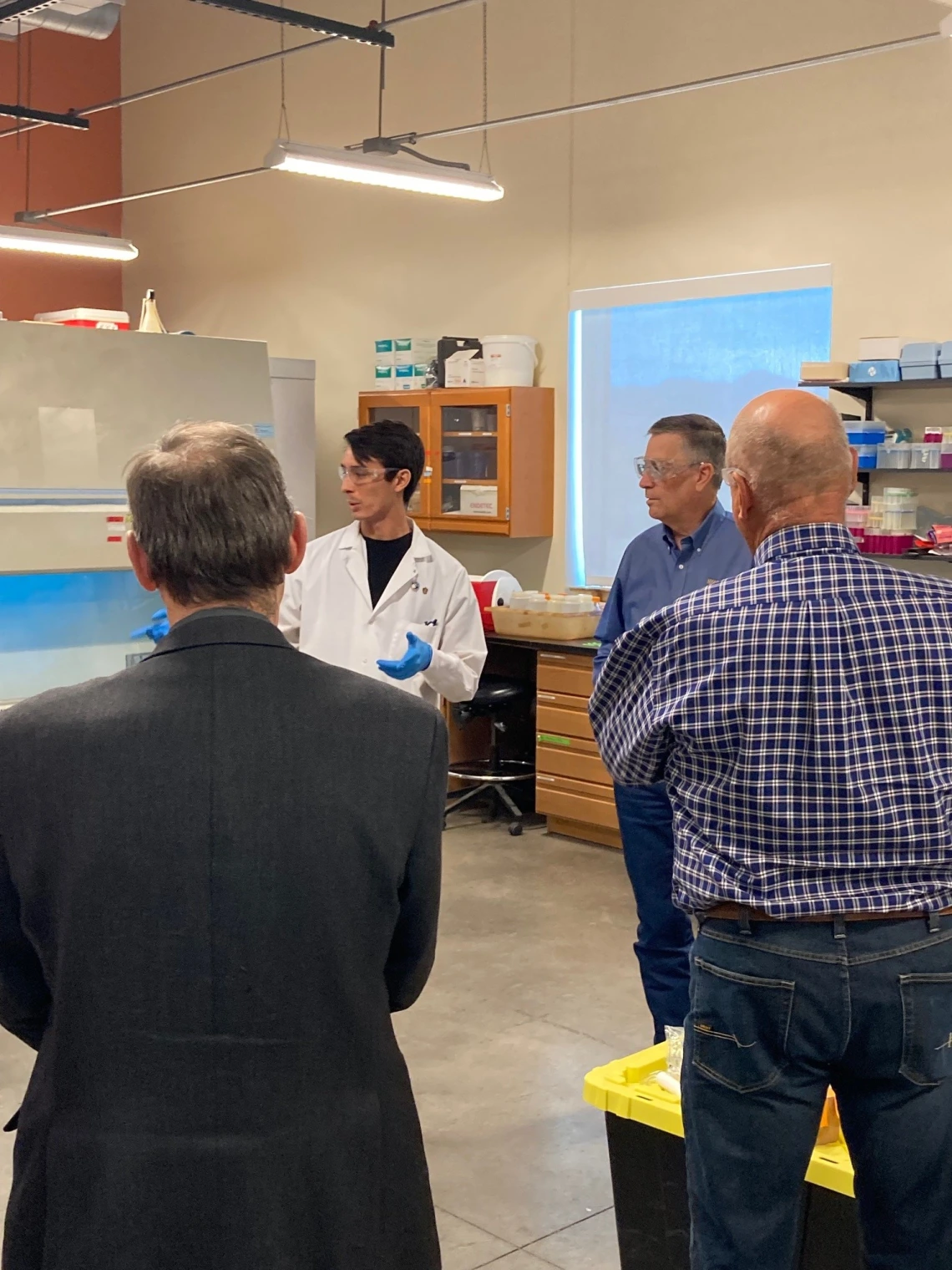 A person in a lab coat talks to a small group