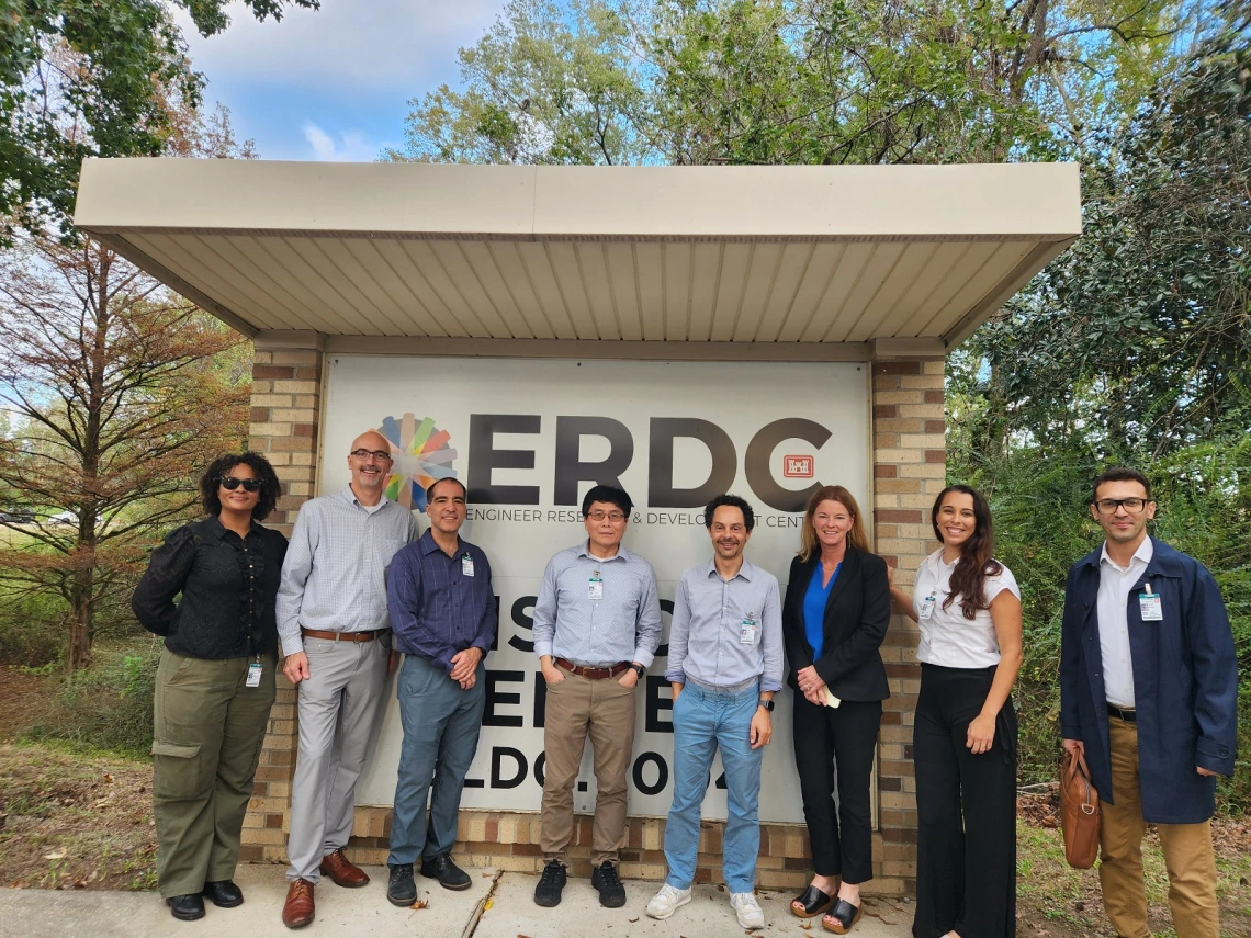 A group of people stand in front of an Army ERDC entry sign