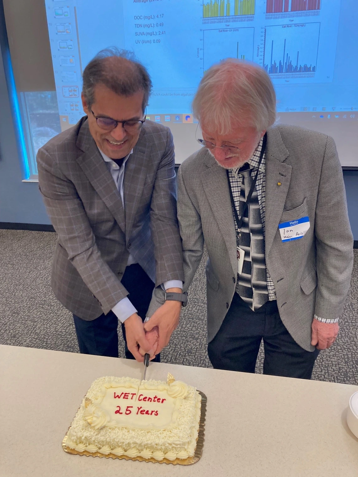 Two men cutting celebratory cake.