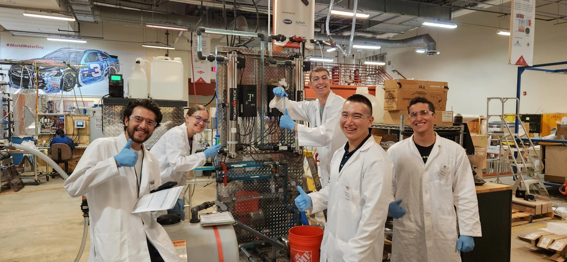 Students wearing lab coats working with water purification equipment