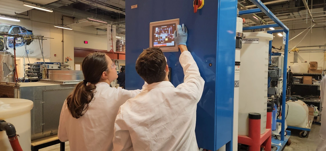 Two workers reading laboratory instrument screen