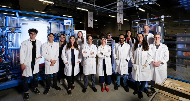 A group of people wearing lab coats in a high bay laboratoy.