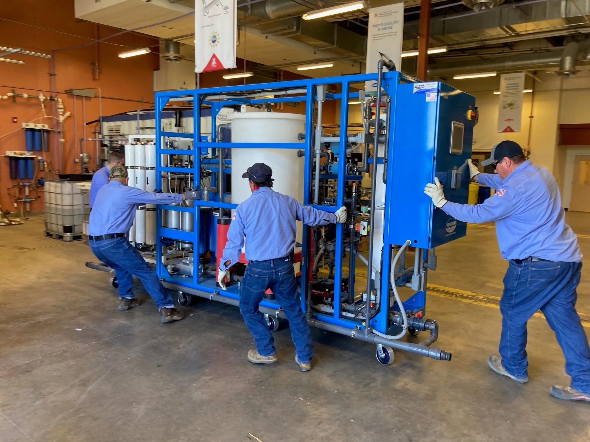 Water reuse equipment being moved into the WEST center by workers